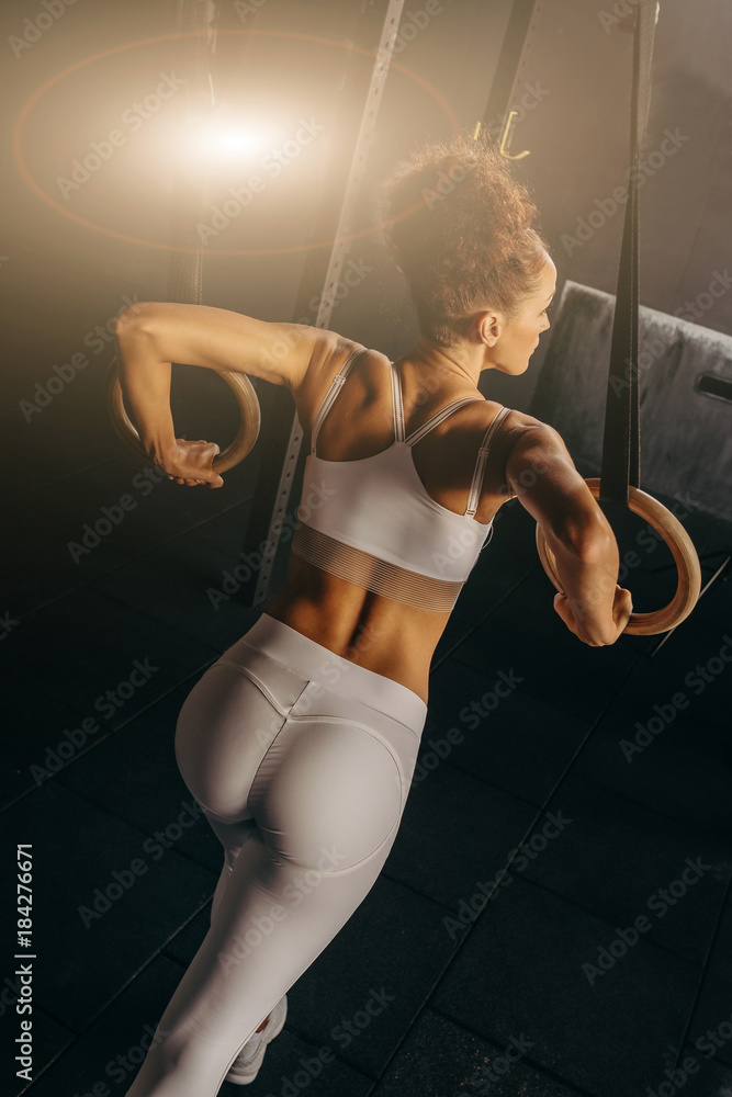Strong fitness model in sportswear. Lifestyle. Crossfit woman standing with  her back in gym. Fitness girl with trained body. Bodybuilder in sports  club. Perfect gymnastic sexy buttocks in leggings. Stock Photo