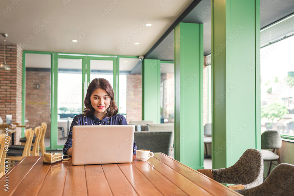 Beautiful cute asian young businesswoman in the cafe, using laptop and drinking coffee smiling Beautiful cute asian young businesswoman in the cafe, using laptop and drinking coffee smiling