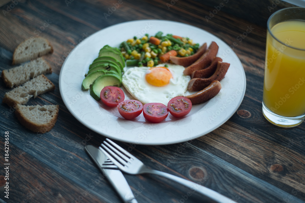 English breakfast. Fried eggs, sausages, avocado, beans, toasts, tomatoes, orange juice on wooden table. Top view with copy spac English breakfast. Fried eggs, sausages, avocado, beans, toasts, tomatoes, orange juice on wooden table. Top view with copy spac