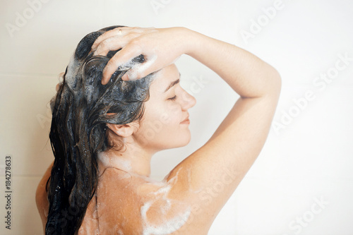 the girl washes her hair in the shower, girl stands with his back to the camera in the shower, girl taking a shower from the bathroom, steam coming, happy girl takes a shower