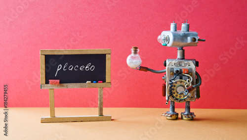 Placebo effect concept Medic robot drugs tube, black chalkboard with handwritten word placebo. Pink wall brown floor background. photo