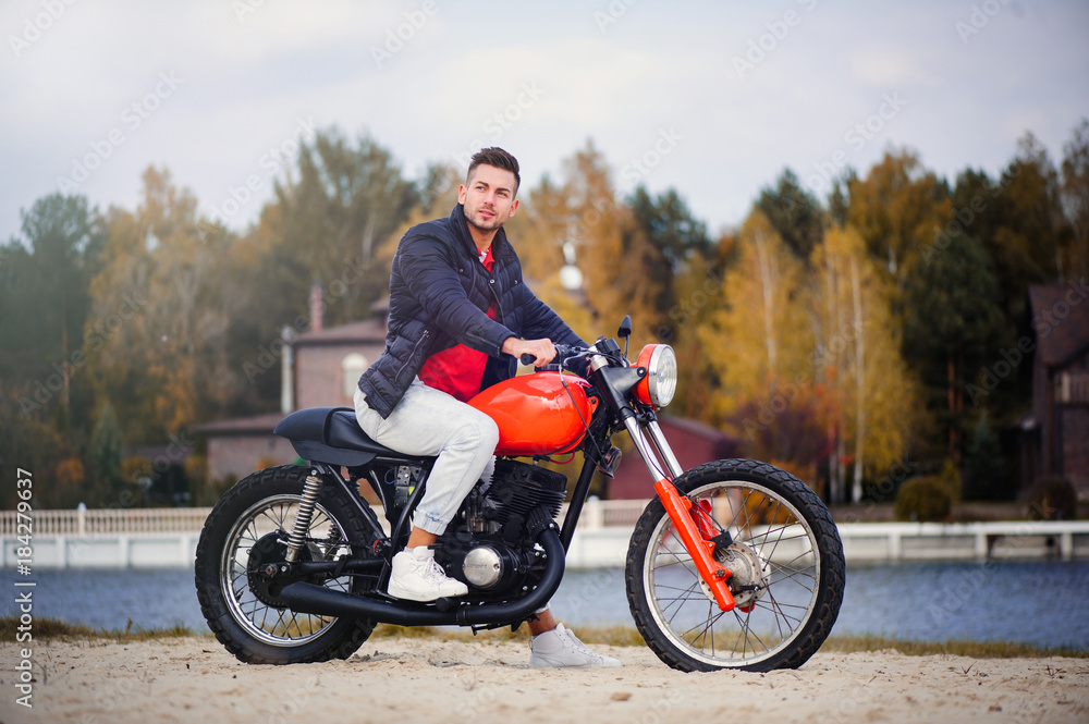 Obraz premium young sports fashionable man on a motorcycle, a warm shot, late autumn