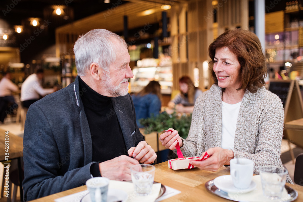Senior couple with a present in a cafe. Christmas time. Senior couple with a present in a cafe. Christmas time.