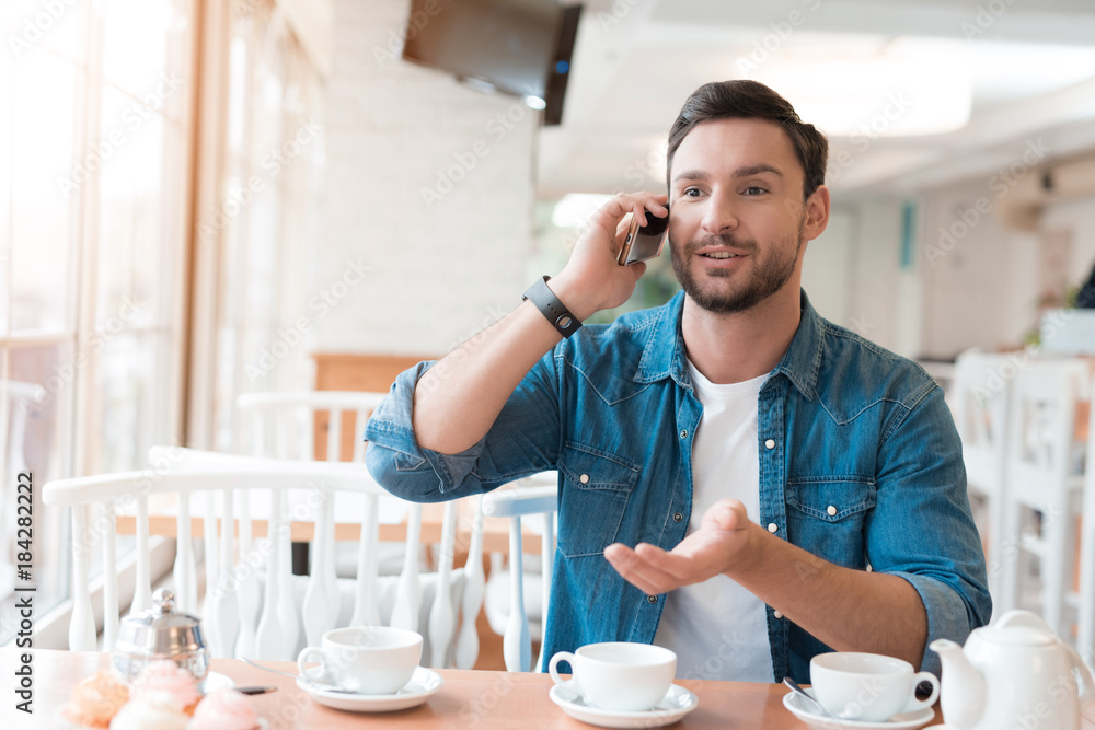 The guy is talking on the phone in a cafe. The guy is talking on the phone in a cafe.