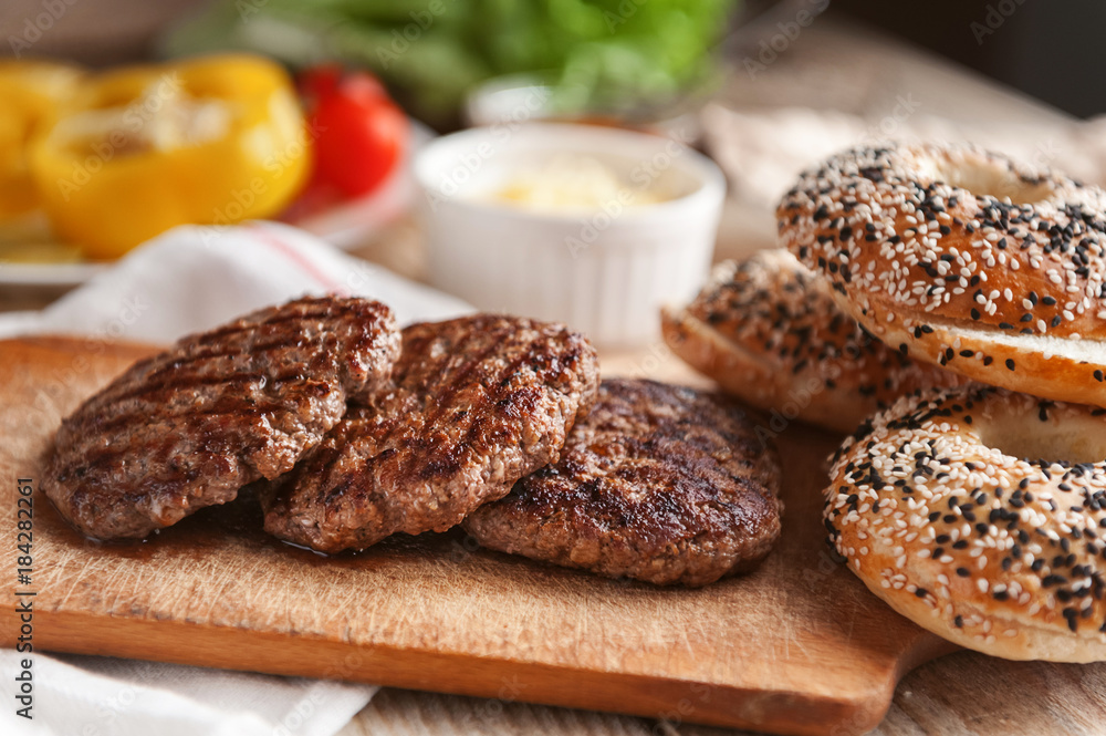 Ingredients for a delicious home burger on a wooden background. roll, bagel, with a juicy cutlet from beef, sauces cheese fresh lettuce leaves Ingredients for a delicious home burger on a wooden background. roll, bagel, with a juicy cutlet from beef, sauces cheese fresh lettuce leaves