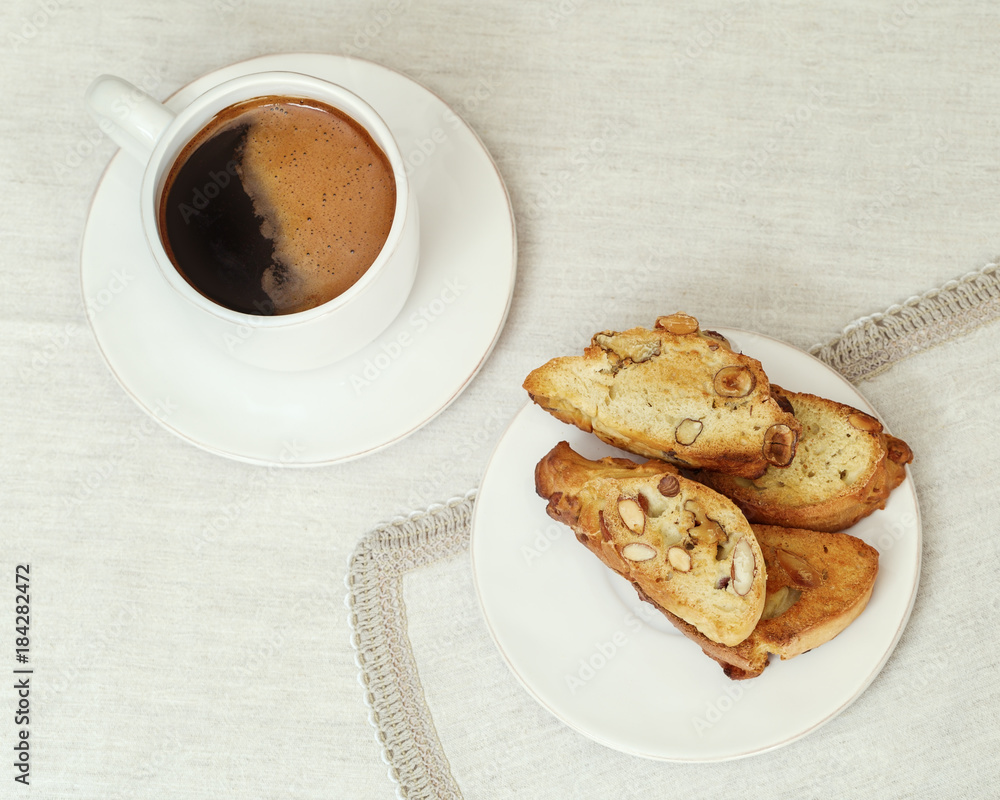 A Cup of coffee and cookies biscotti on the table in a white porcelain ware. Selective focus. Copy space. Top view. Retro toning. A Cup of coffee and cookies biscotti on the table in a white porcelain ware. Selective focus. Copy space. Top view. Retro toning.