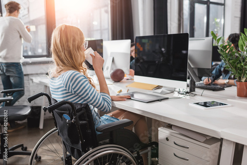 Fototapeta incapacitated person in wheelchair working at modern office