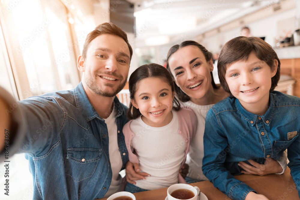 Mom, dad, daughter and son posing together on a camera in a cafe. Mom, dad, daughter and son posing together on a camera in a cafe.