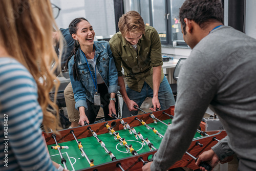 Foto happy multicultural people playing in table soccer at modern office