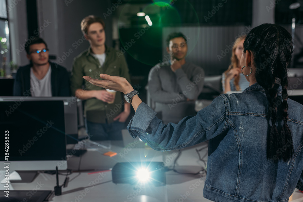 Fototapeta premium young people watching presentation in modern office, woman pointing on screen