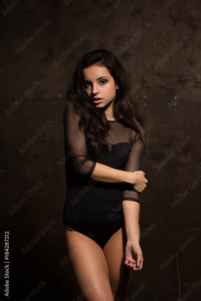 Seductive brunette woman with perfect body and long hair posing in black lingerie. Shadow and light Seductive brunette woman with perfect body and long hair posing in black lingerie. Shadow and light
