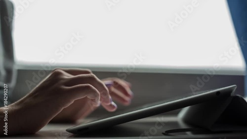 Young girl typing and working with the tablet. Close-up of hands with manicure.