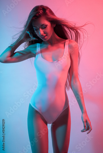 Beautiful woman in pink swimwear posing at camera against colorful background