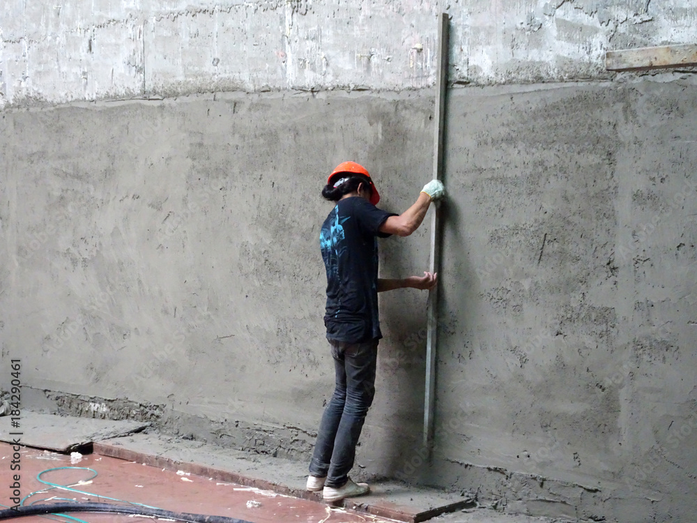 Construction workers plastering building wall using cement plaster with mix  of cement, sand & lime at the construction site. foto de Stock | Adobe Stock