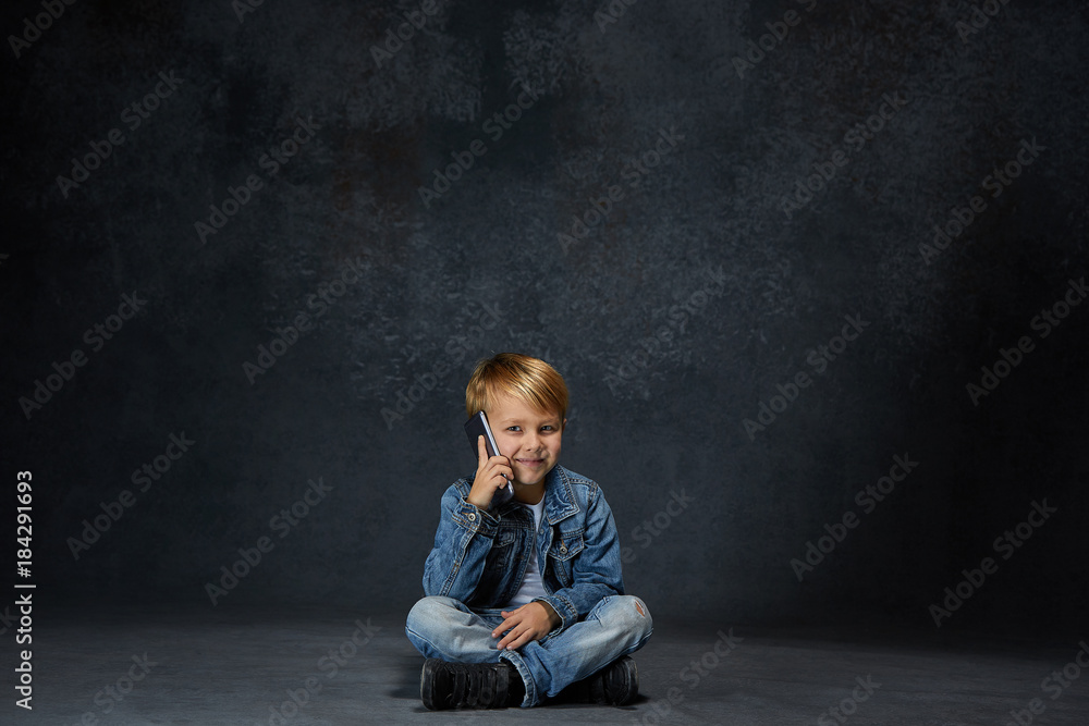 Little boy sitting with smartphone in studio Little boy sitting with smartphone in studio