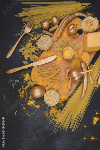 Italian food .Golden ingredients for cooking pasta with board on dark background.Top view