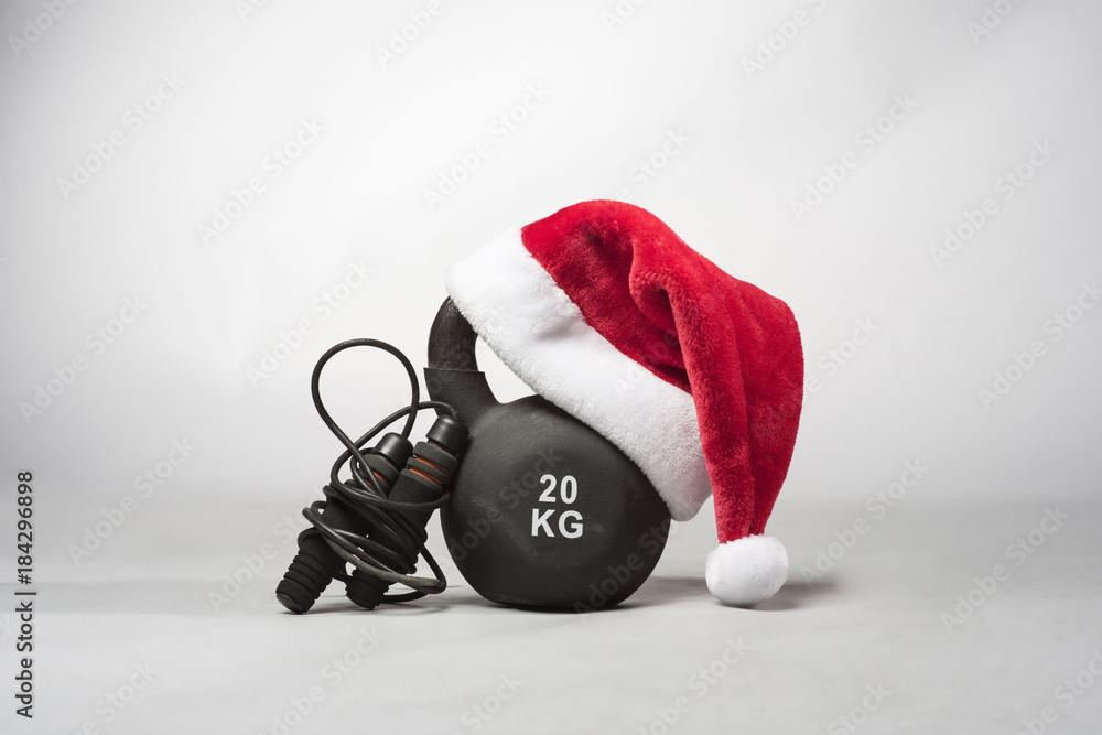 A large black Kettlebell wearing a red Santa hat with a skipping rope