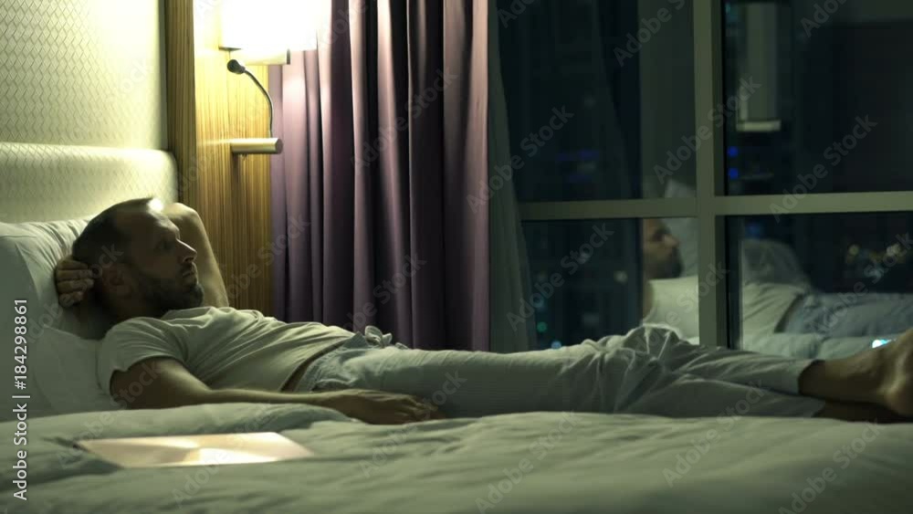 Sad, unhappy man lying on bed during night
Sad, unhappy man lying on bed during night