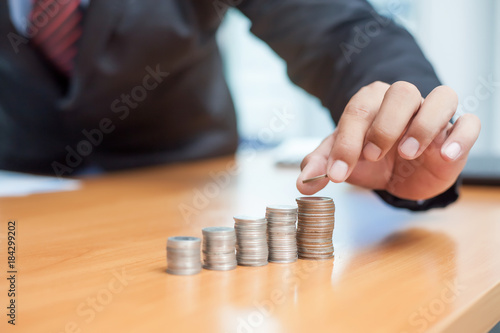 Businessman hand put coins to stack of coins. Business growth concepts