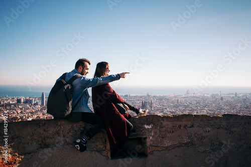 Couple looking at the cityscape of Bacrelona. Man point the finger at smth