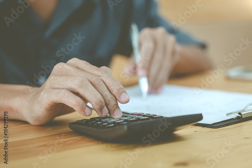 Man using calculator and writing make note with calculate about cost