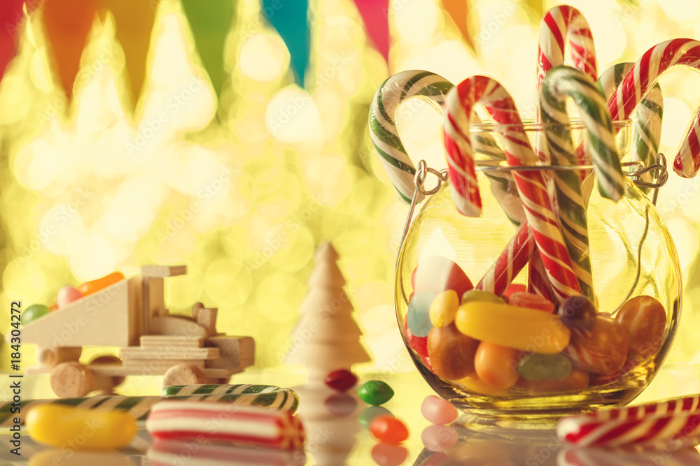Fototapeta premium Cane caramel, in a glass jar. All for a sweet nice holiday. Children's card. Ready greeting. Retro toning.