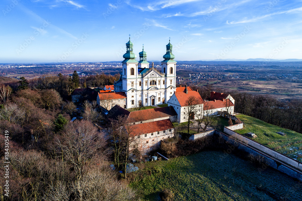Camaldolese monastery and baroque church in the wood on the hill in Bielany, Krakow, Poland , Aerial view in winter with far view of Cracow city in the background