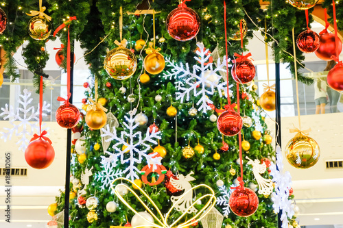 Many colorful christmas ball hang by ribbin with fake christmas tree for background (Selective Focus)