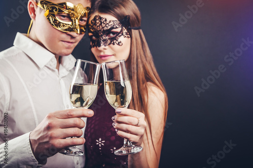 Couple celebrating New Year's eve drinking champagne on masquerade party