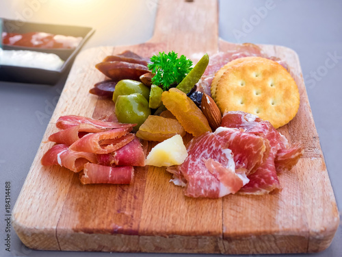 Antipasto catering platter with bacon, jerky, sausage, blue cheese, almond and biscuits on a wooden background photo