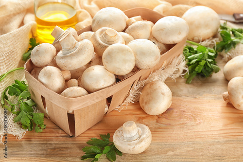 Basket with fresh champignon mushrooms on table