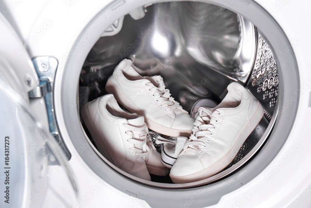 Many white sneakers in washing machine, closeup Many white sneakers in washing machine, closeup