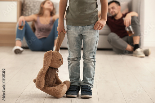 Little boy holding toy bunny while his parents drinking alcohol on background photo