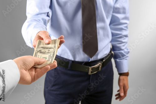 Woman giving money to man on light background