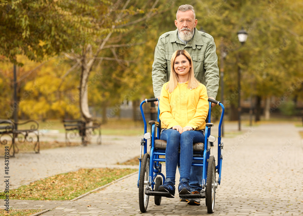 Senior man with his daughter in wheelchair outdoors on autumn day Senior man with his daughter in wheelchair outdoors on autumn day