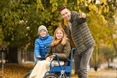 Teenage girl in wheelchair with her family outdoors on autumn day © Africa Studio
