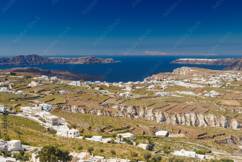 rocky plateau whith white houses in Greek island Santorini with blue surface of the sea and other islands in the background