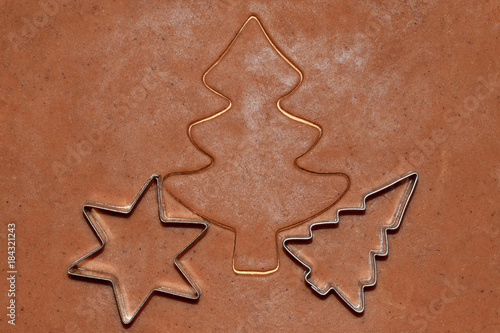 Cutting out Christmas gingerbread cookies with metal cutters- trees and star