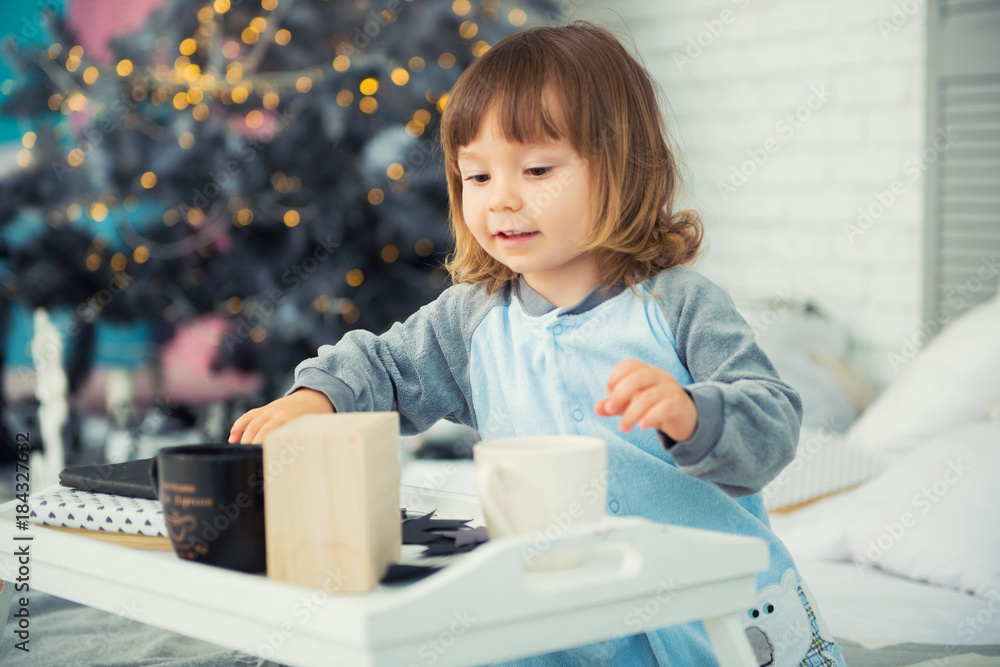 Emotional smiling little girl sitting in pajama with Christmas gifts near New Year's tree and playing snowballs Emotional smiling little girl sitting in pajama with Christmas gifts near New Year's tree and playing snowballs