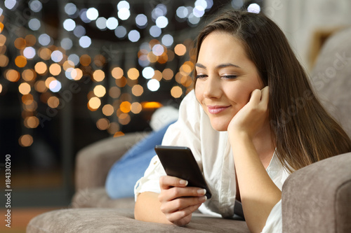 Relaxed woman using a smart phone lying on a couch