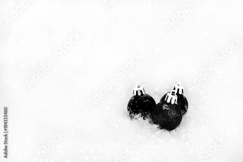 Christmas balls black white on white snow background.