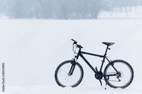 Winter season cycling. Black bicycle on the snow. Sport at any time of year concept.