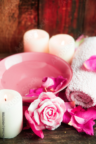 Spa settings with roses. Fresh roses and rose petals in a bowl of water and various items used in spa treatments