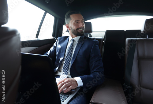 man with laptop sitting in the back seat in the car © ASDF