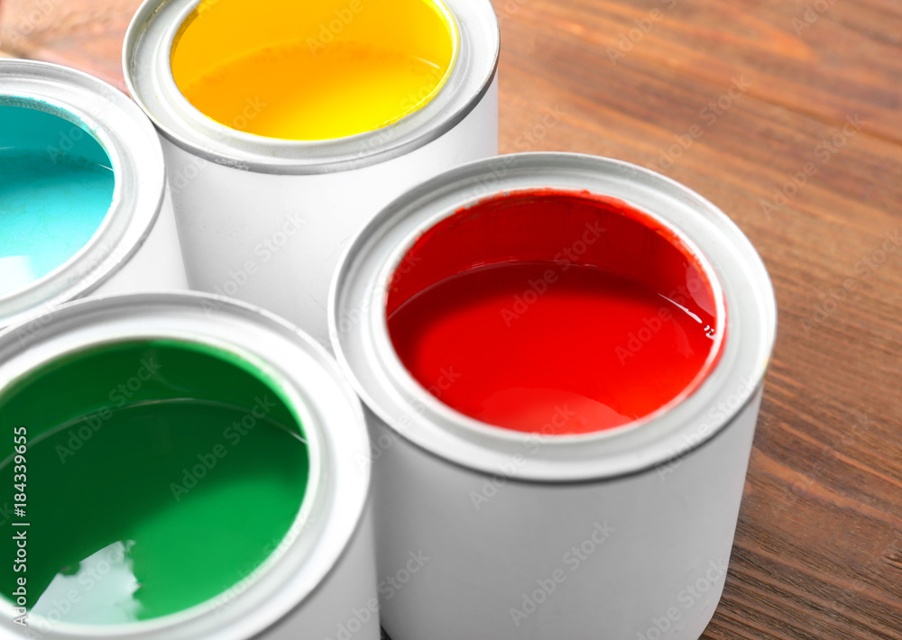 Multicolored paint in tin cans on wooden background, closeup Multicolored paint in tin cans on wooden background, closeup