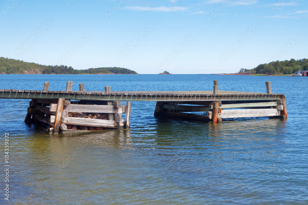 Wooden bridge in the blue sea, islets in the Finish archipelago in the background