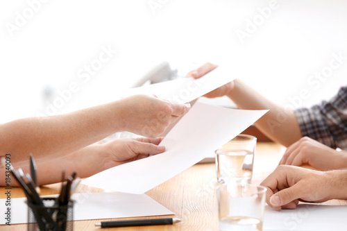 Woman handing documents to her clients on meeting with consultant