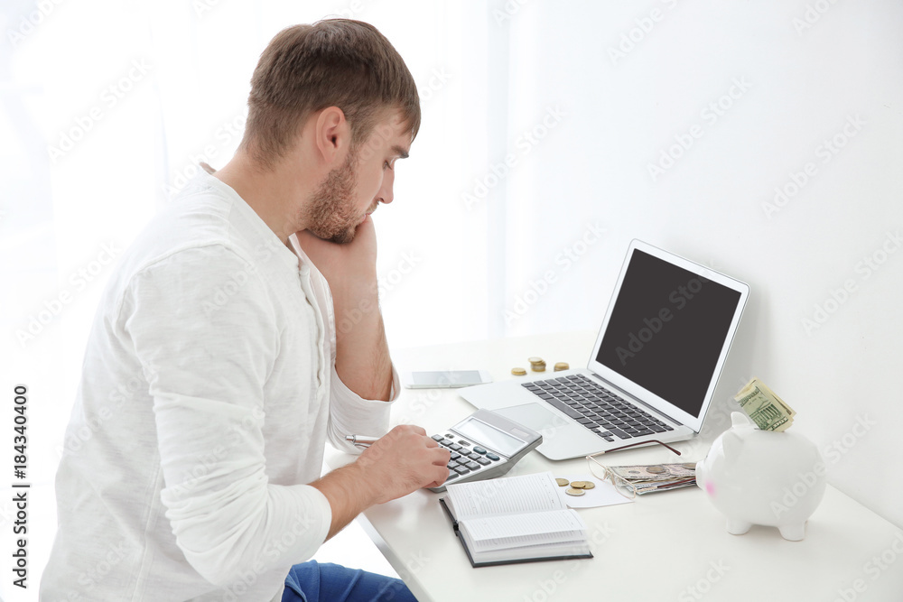 Young man counting taxes at table indoors Young man counting taxes at table indoors