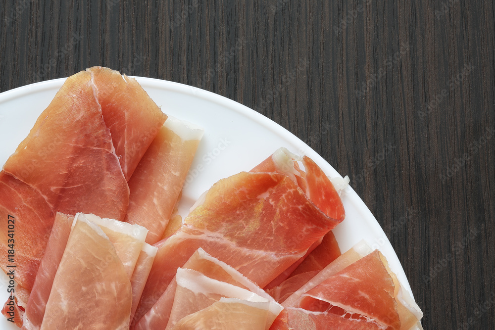 Sliced jamon (hamon) or prosciutto on a wooden background Sliced jamon (hamon) or prosciutto on a wooden background
