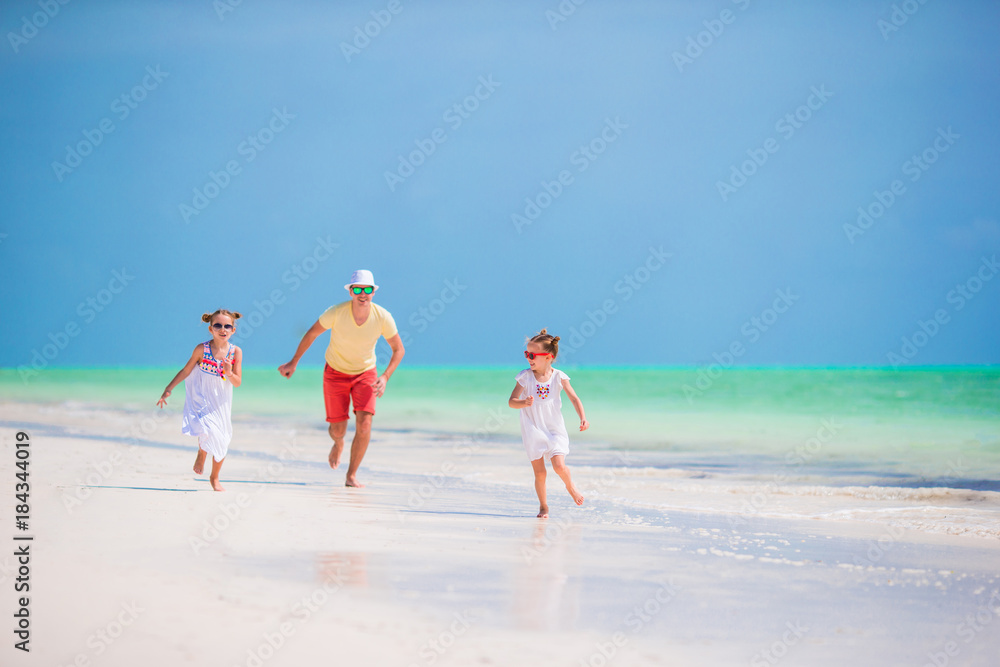 Family walking on white beach on caribbean island. Father have fun with daughters on the beach